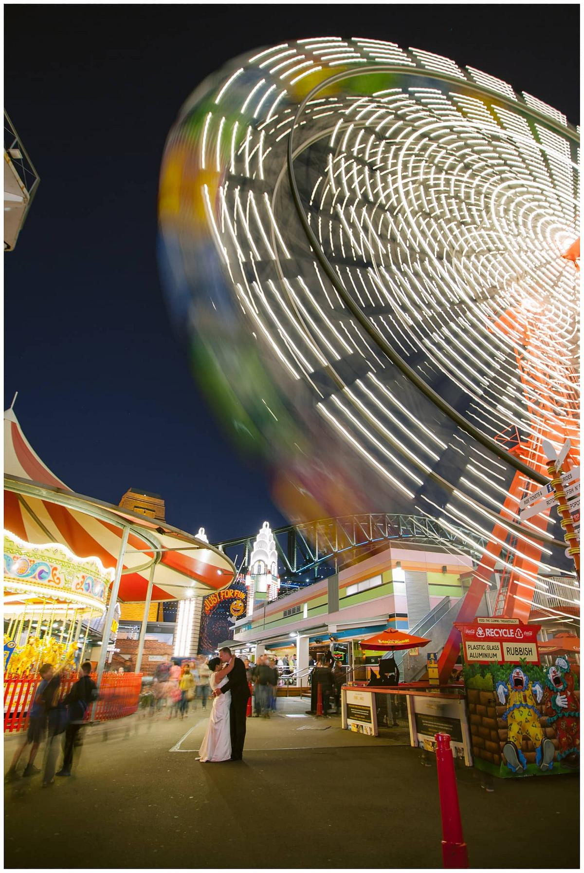 Night photography of wedding couple under the Ferris Wheel at Luna Park Sydney.