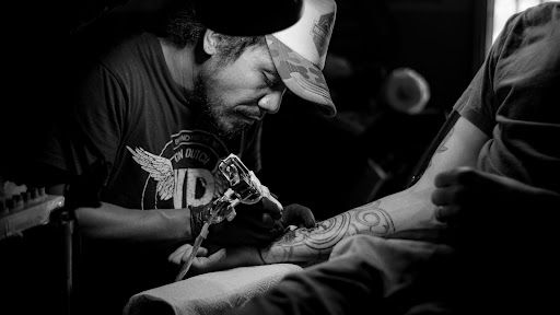 Artysta wykonujący tatuaż na prawym ramieniu